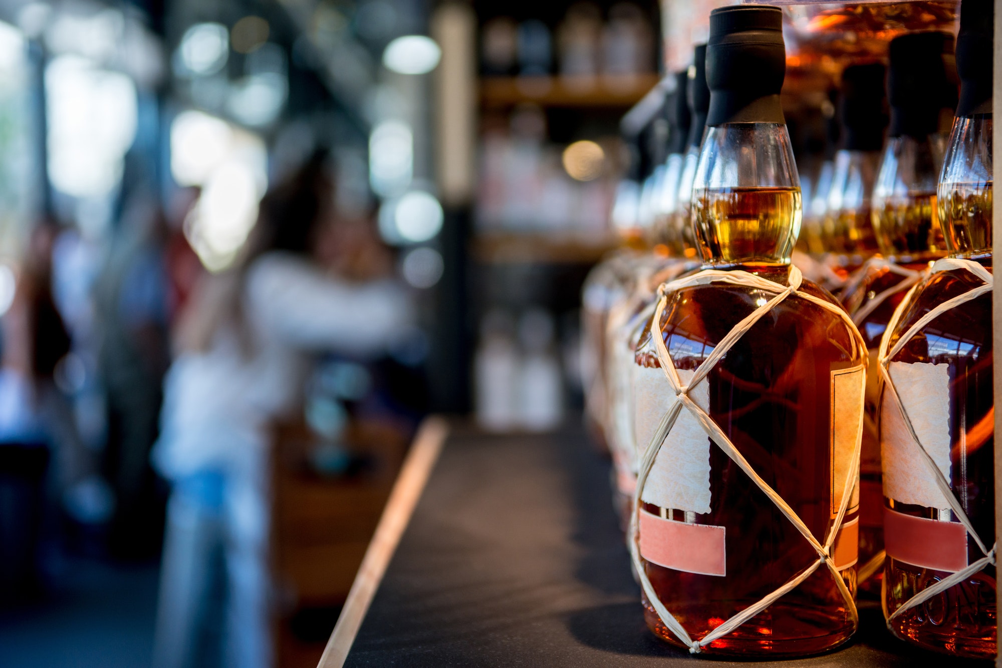 selective focus of whiskey bottles placed in rows on shelf in store